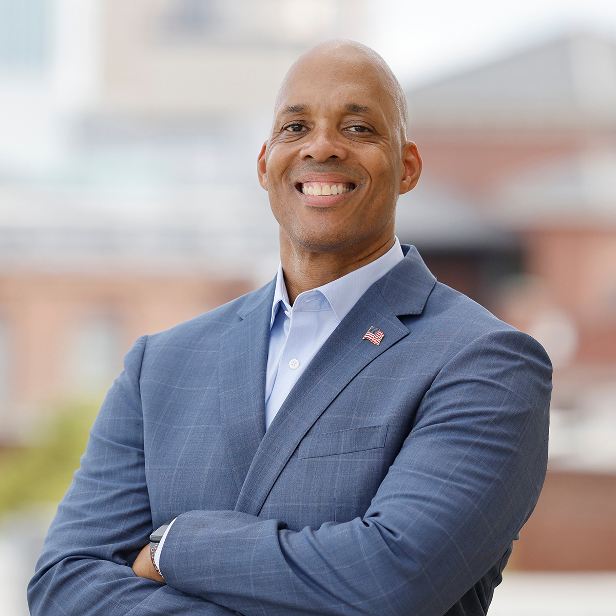 Professional headshot of Dr. Darren McAuley wearing a blue-gray suit in front of a hospital.